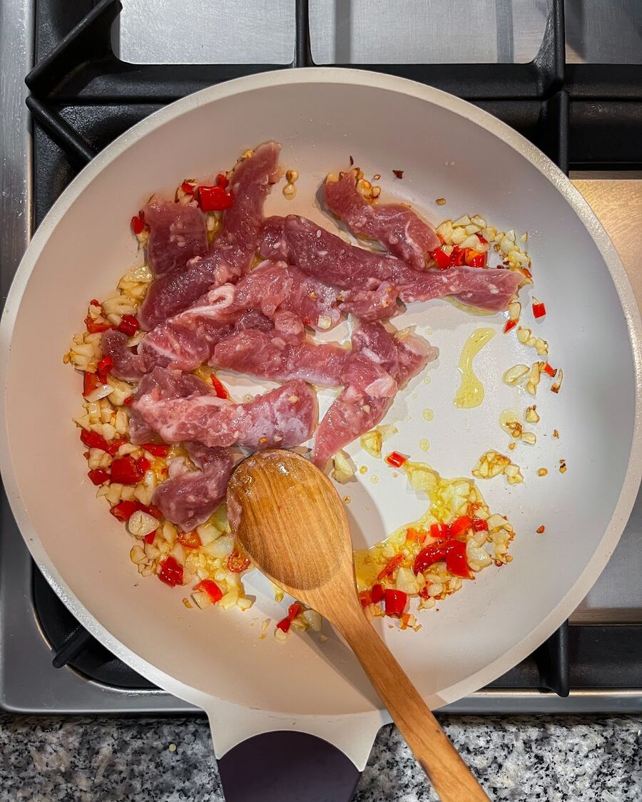 Add sliced pork and continue stirring until fully cooked.