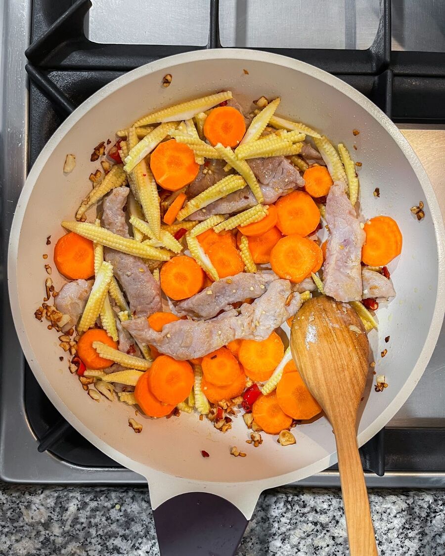 Add baby corn and carrots, and continue stirring until the vegetables are softened.