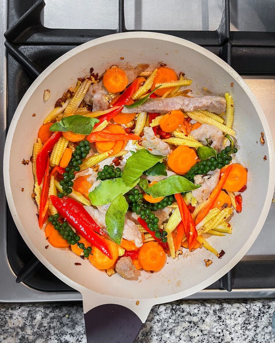 Continuously stir the ingredients, then add kaffir lime leaves (which should be squished by hand to release more fragrance), baby pepper, and finger root.
