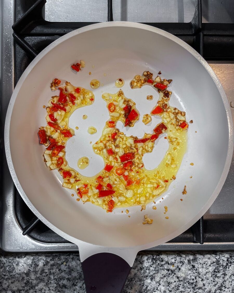 Place a wok or pan on medium-high heat. Once hot, add cooking oil, minced chili and garlic. Continuously stir the mixture until it emits a fragrant aroma.