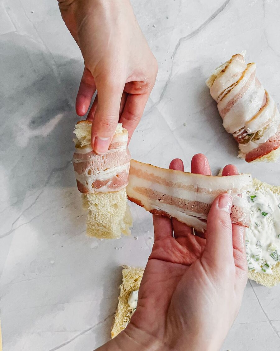 Wrap each cylinder of bread with a slice of bacon for a savory and delicious bite.