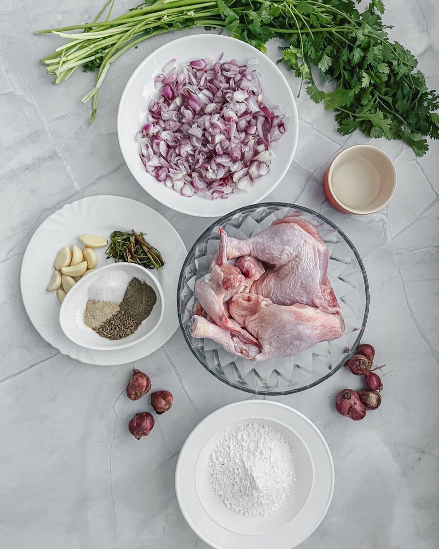 Gather all ingredients. Slice shallot into even pieces for fried shallots. In a separate bowl, mix together the following spices and marinade ingredients: garlic, white and black pepper, cumin seed, salt, carainto stem and roots, rice flour, water. Add chicken with bone and skin to the marinade mixture.  