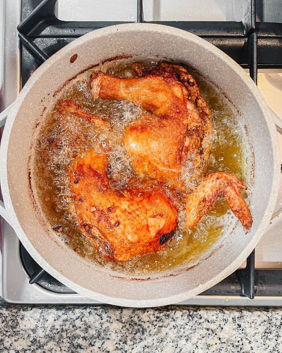 Cook chicken in oil for approximately 10 minutes, then flip and continue cooking for an additional 10 minutes or until it turns a dark brown. The cooking time may vary depending on the size of the chicken.