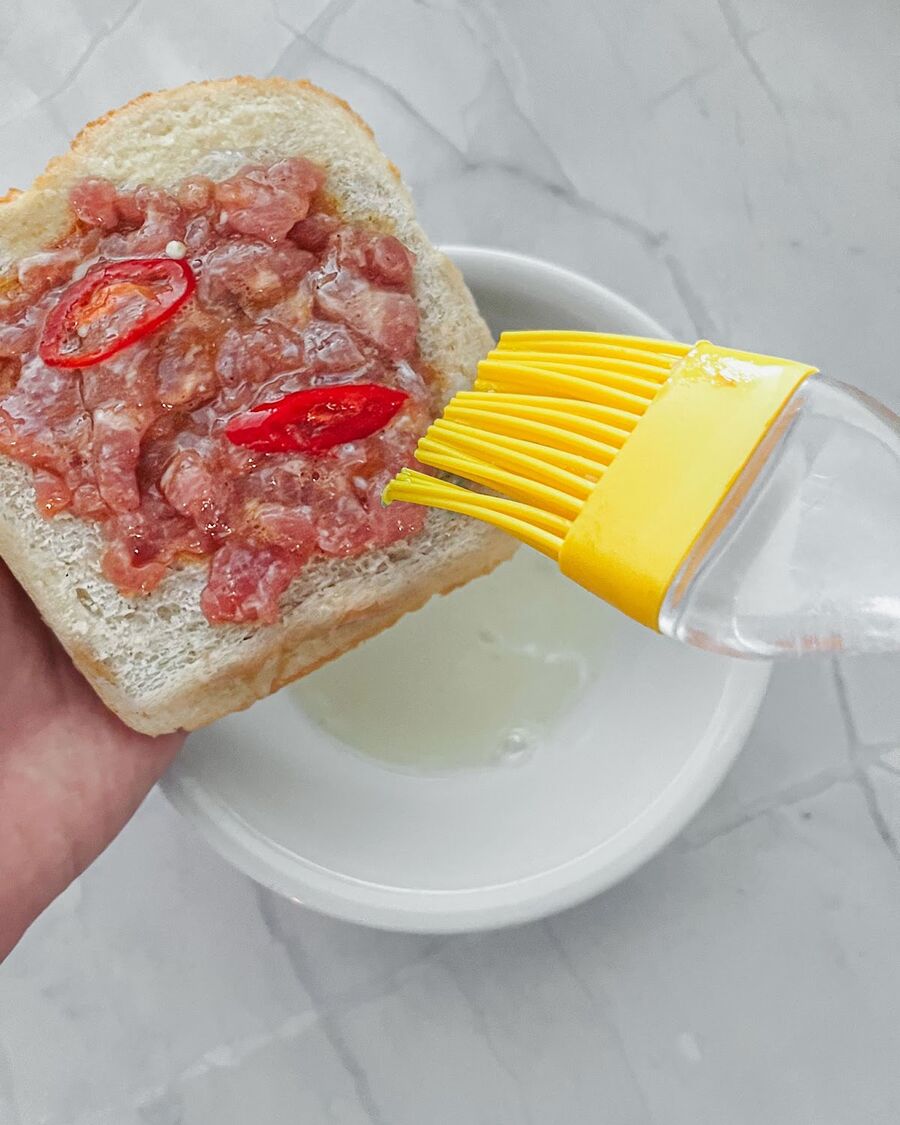 Brush the top of the mixture with egg white to cover the pork mixture and help it stick to the bread.