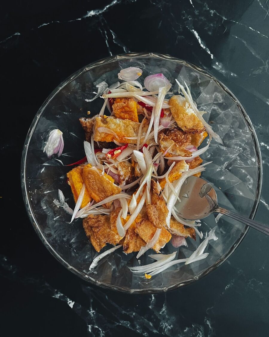 Combine the cut fried egg, onion, shallot, and tomato in the bowl containing the salad dressing mixture. Thoroughly mix the ingredients together until well combined.