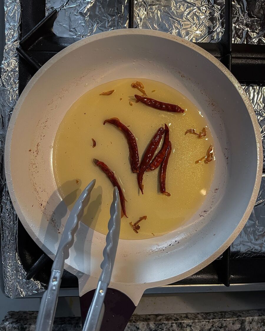 After removing the fried shallots, turn off the heat and add the dried chilies to the same oil. Stir them for about 30 seconds and then remove them from the oil.