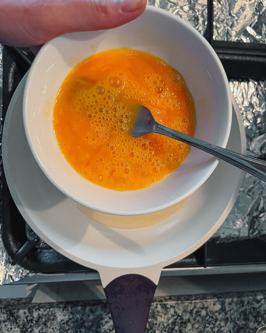 Using the same pan and cooking oil from the fried garlic, fry the Thai omelette over medium-high heat to achieve a crispy texture. Crack the egg into a bowl and beat it with a fork..