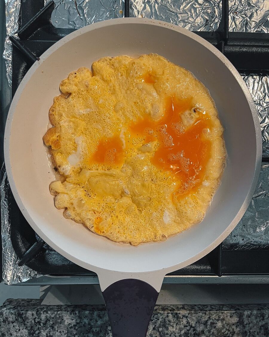 Add the beaten egg into the pan with the hot oil. Fry the egg for about a minute or until it turns golden brown. Then, flip the egg and fry the other side until it becomes golden brown as well. Once the egg is fully cooked, remove it from the oil.
