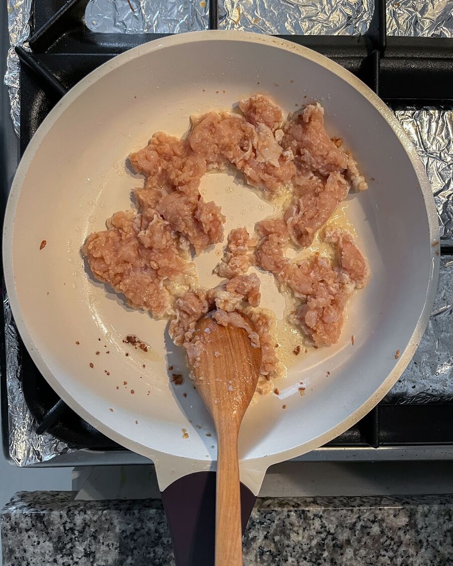 Using the same cooking oil that was used to fry the egg, add the chicken and cook until it is halfway done.