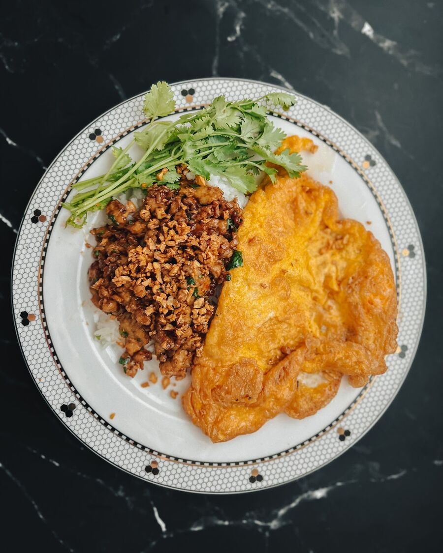 Serve the garlic pepper chicken on top of steamed rice and Thai omelette. Add Sriracha sauce to taste. Garnish the dish with crispy fried garlic. Enjoy!