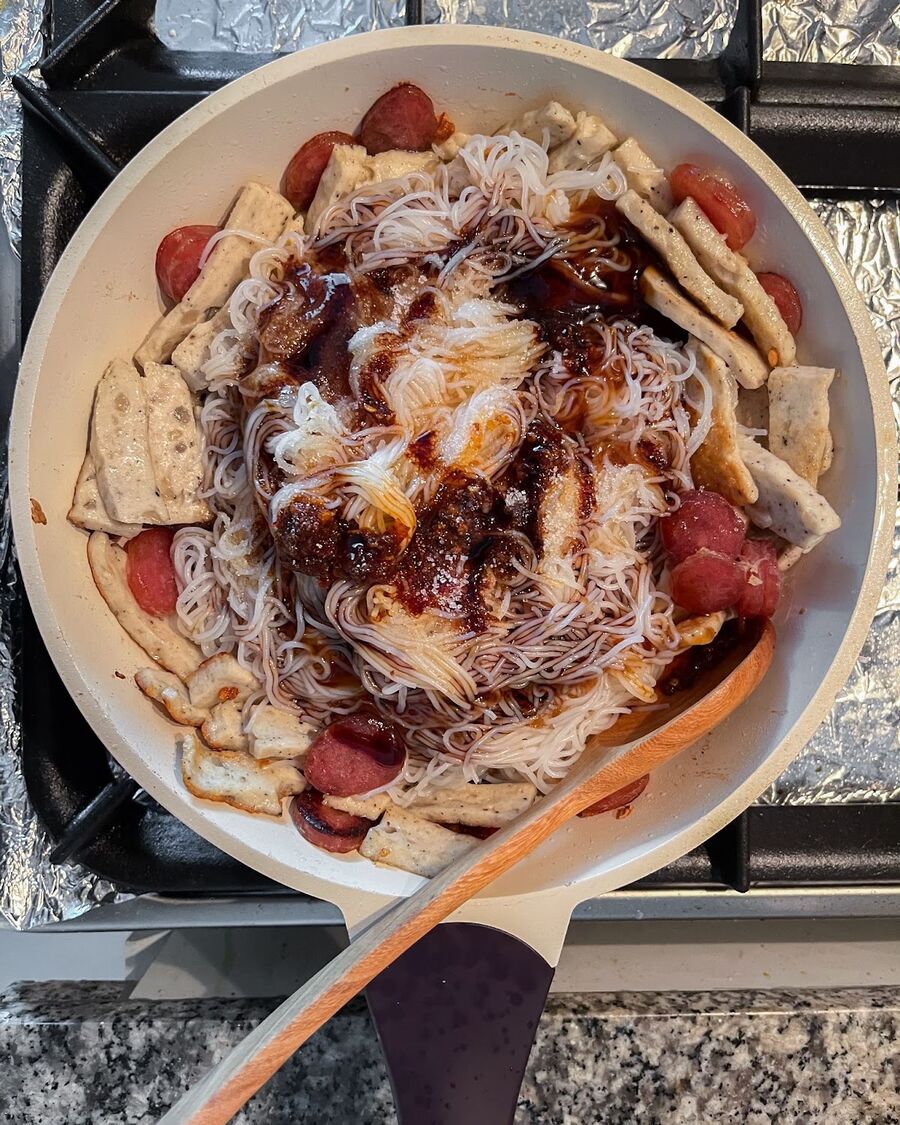 Add the fermented rice noodles to the pan, followed by the mixed sauce ingredients. Stir continuously to ensure the sauce coats the noodles evenly.