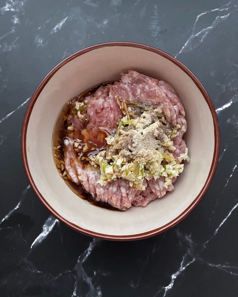 Blend garlic and cilantro root in a food processor, then mix the resulting paste with ground pork along with soy sauce, sesame oil, and ground pepper. Ensure that everything is well blended.