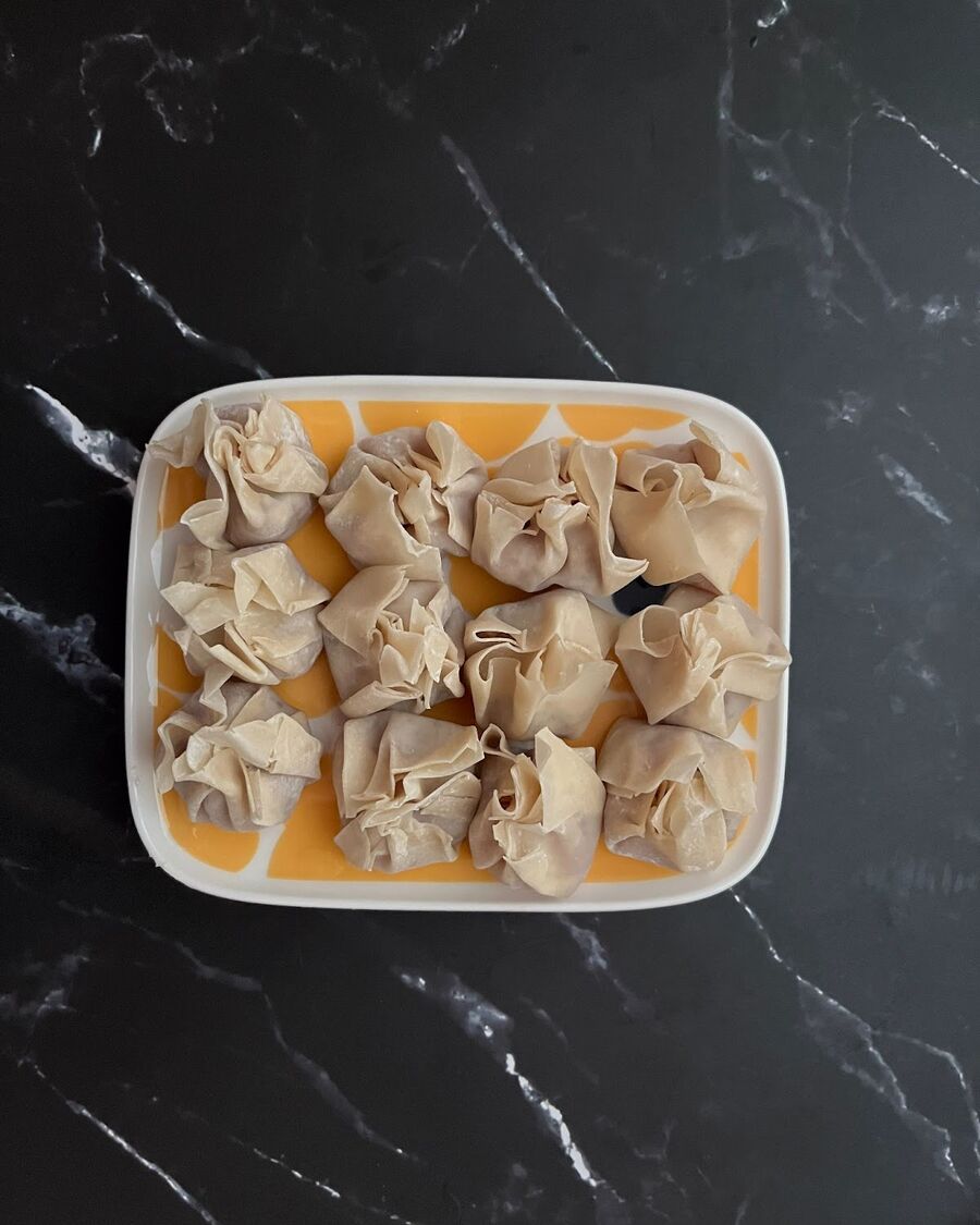 To fill the wonton, take one teaspoon of the ground pork mixture and place it in the center of each wrapper. Then, wet the edges of the wrapper using your finger and fold all four corners up and over the filling. Press down gently to seal the wonton.