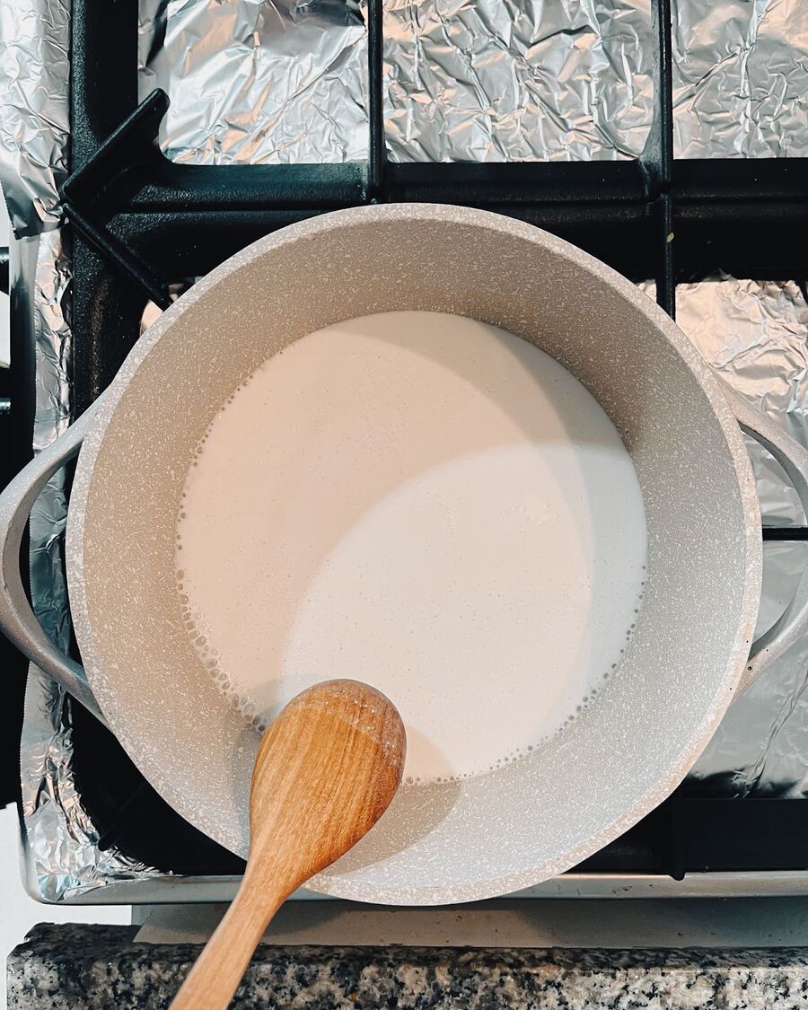Heat a pot over medium-high heat. Once the pot has reached the desired temperature, pour in the coconut milk and begin stirring consistently. Continue stirring until you observe the coconut milk starting to release oil, indicated by the formation of bubbles around the edges of the pot. This is a crucial indicator that the coconut milk has reached the appropriate stage for the subsequent step in the process.