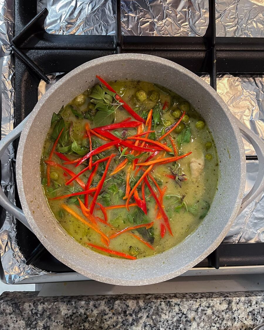 Take the curry off the heat and add sweet basil and sliced red chillies. Stir everything together to ensure the flavors are well combined.