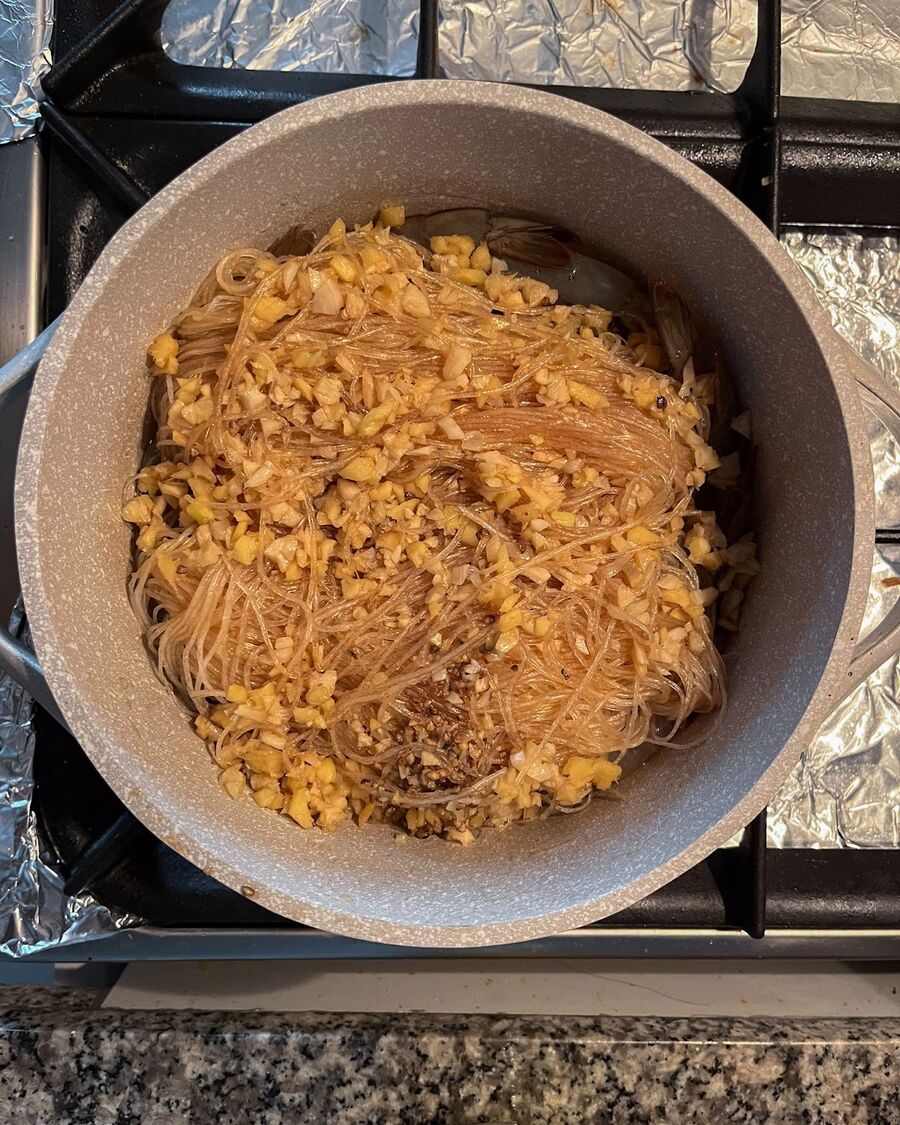 Place the soaked glass noodles, which have absorbed the mixture sauce, on top of the shrimps in the pot.