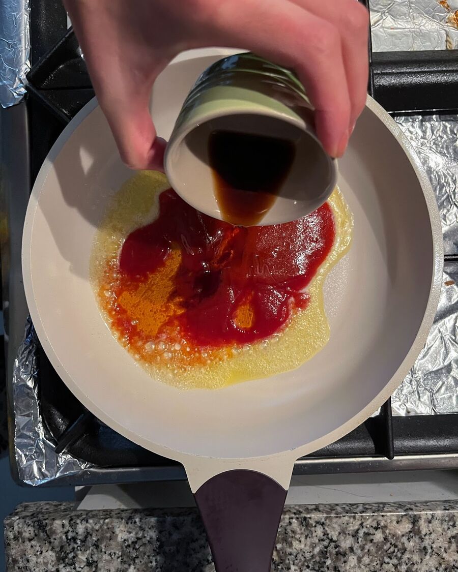 While waiting for the wings to cook, you can prepare the Sriracha sauce. Start by melting the butter cube in a saucepan. Then, mix together the tomato sauce, Sriracha sauce, sesame oil, and soy sauce. Stir the ingredients well to combine them thoroughly.