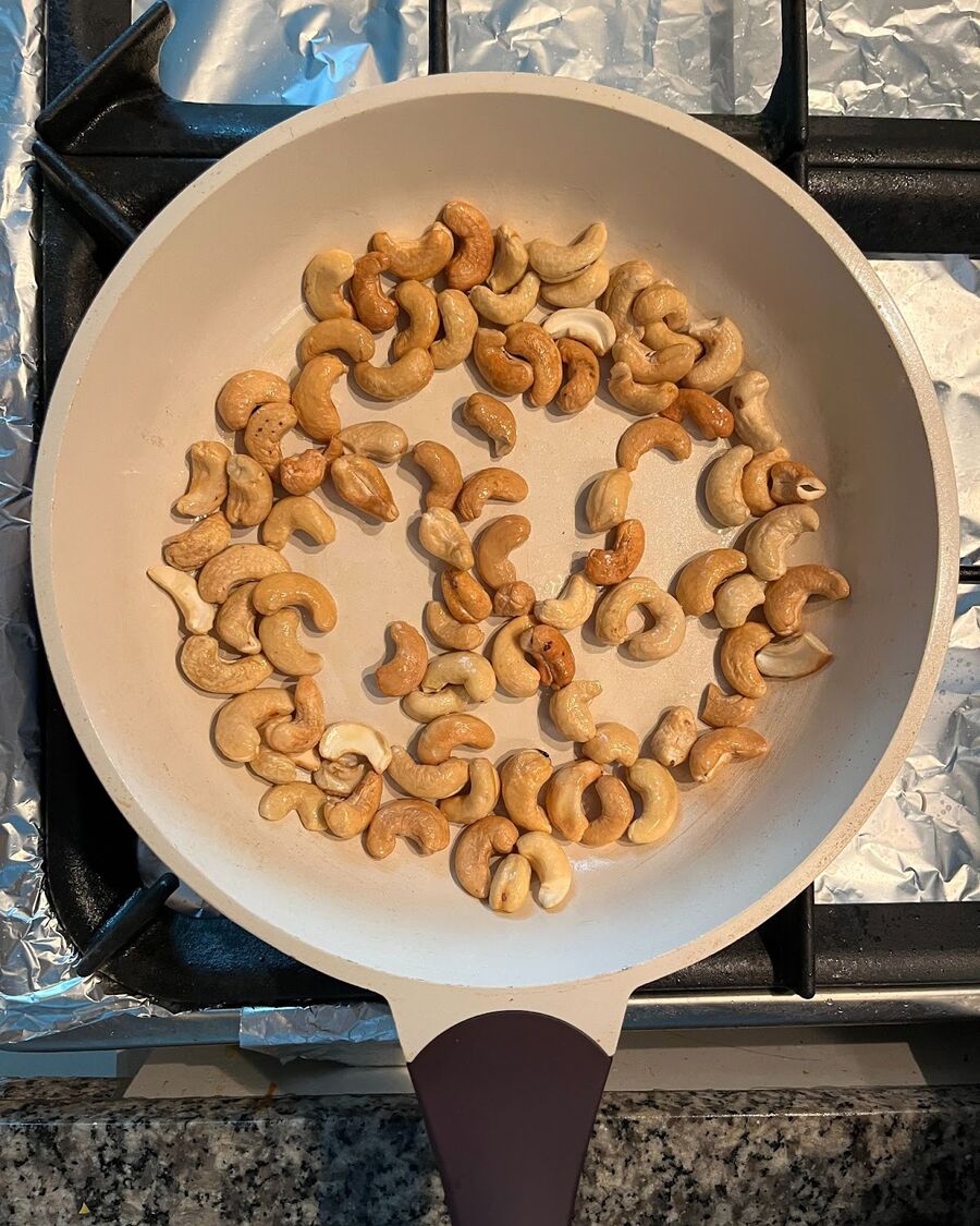 Double roast the cashew nuts in a pan over medium-low heat. Add some olive oil and toast them for about 2-3 minutes until they become fragrant and golden.