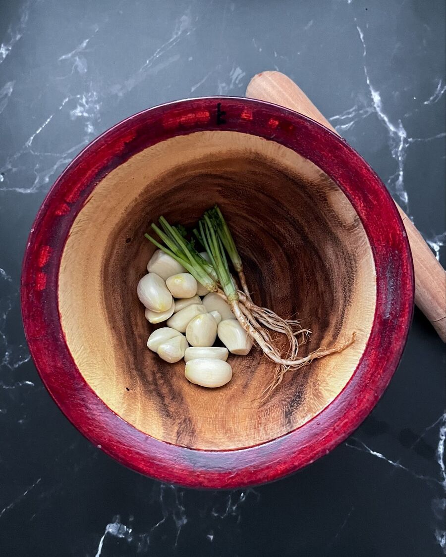 While you are waiting for the water to boil, you can start pounding the garlic and coriander roots together. Continue pounding until they're well combined into a consistent mixture.