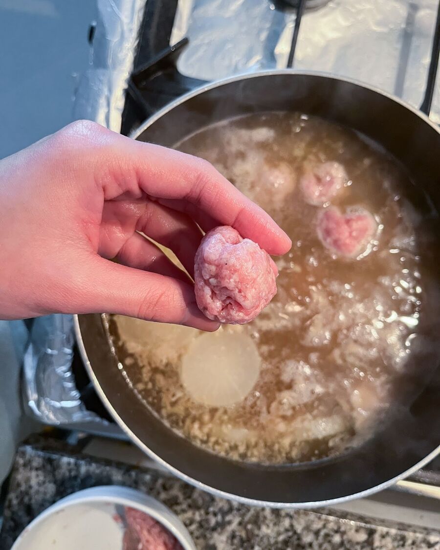 To make the handmade pork balls, roll the marinated minced pork into balls using your hands. You can create any size that suits your preference. Once formed, drop the pork balls into the boiling pork bone pot. Let them cook for about 10 minutes, then reduce the heat and cover the pot with the lid.