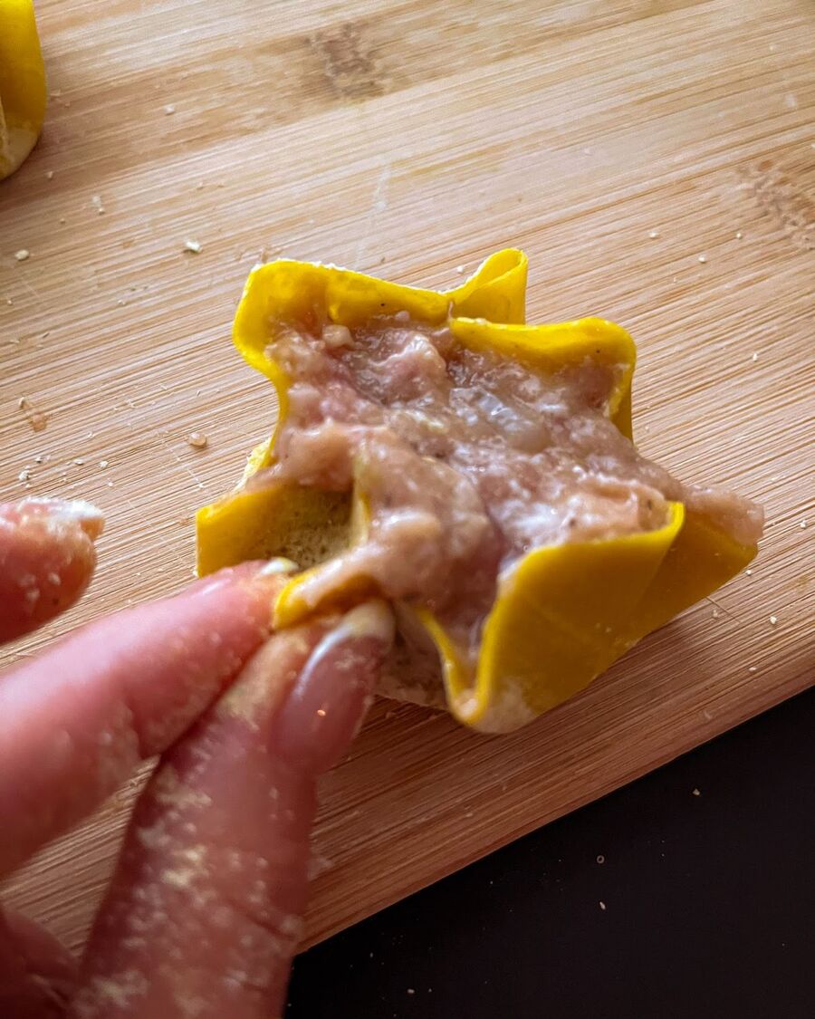 Place approximately 1 tablespoon of the mixed filling in the center of the wonton wrapper. Gently squeeze the wrapper and pleat it to resemble a blooming flower.