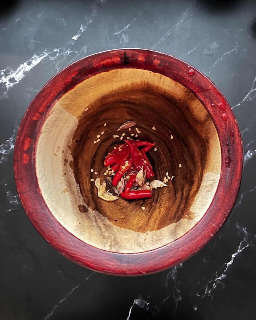 Use a large clay or wooden mortar to crush the chili and garlic.