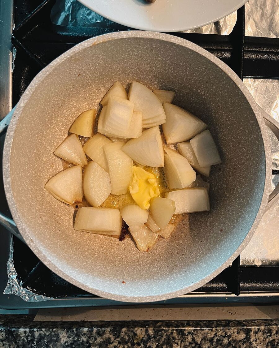 Using the same pot and maintaining the same heat, add 1 tablespoon of butter and onion. Sauté them well until the onions are coated in the oil and butter, allowing them to sizzle as they cook.