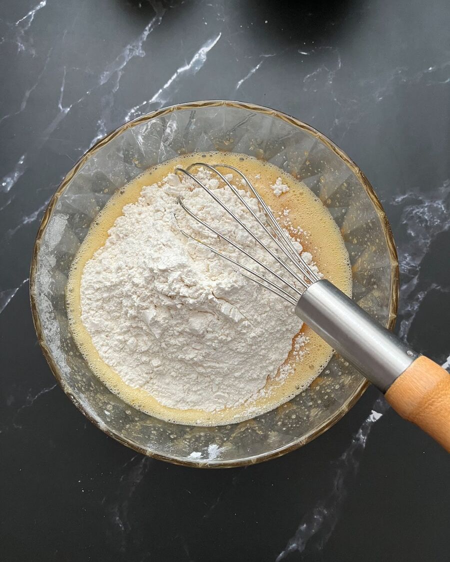 Sift all-purpose flour, baking powder, baking soda, and salt together in a single step. Then, pour the mixture over the beaten eggs. Stir in one direction until well combined.