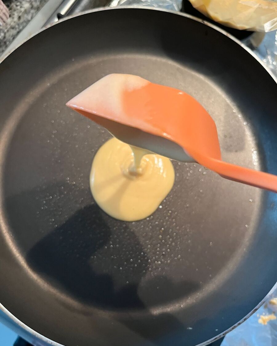 Once the pancake batter is ready, give it one final stir to ensure thorough mixing. Heat the non-stick pan over low heat, then either spray cooking oil, brush with cooking oil, or spread butter over it. Use a ¼ cup to pour the pancake batter into the pan.