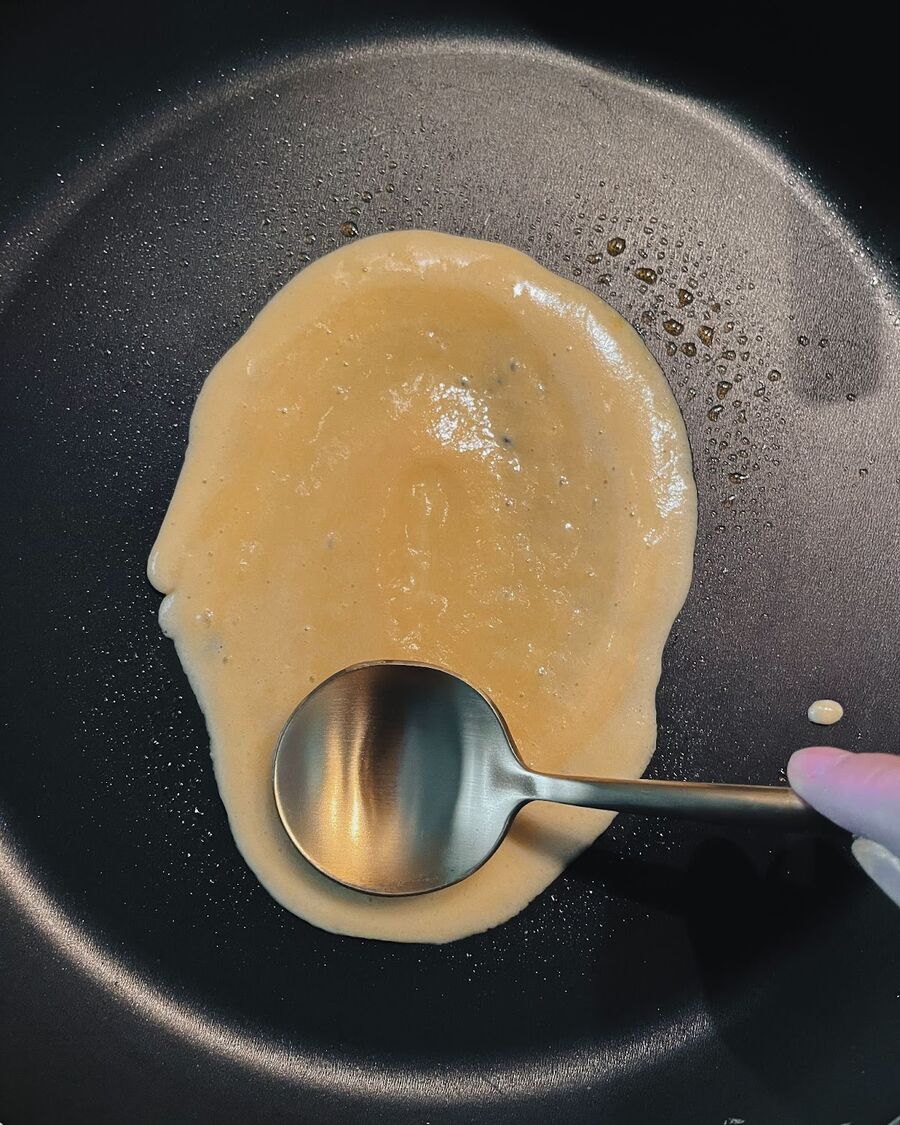 Spread the batter with the bottom of the spoon, shaping it into a thin oval.