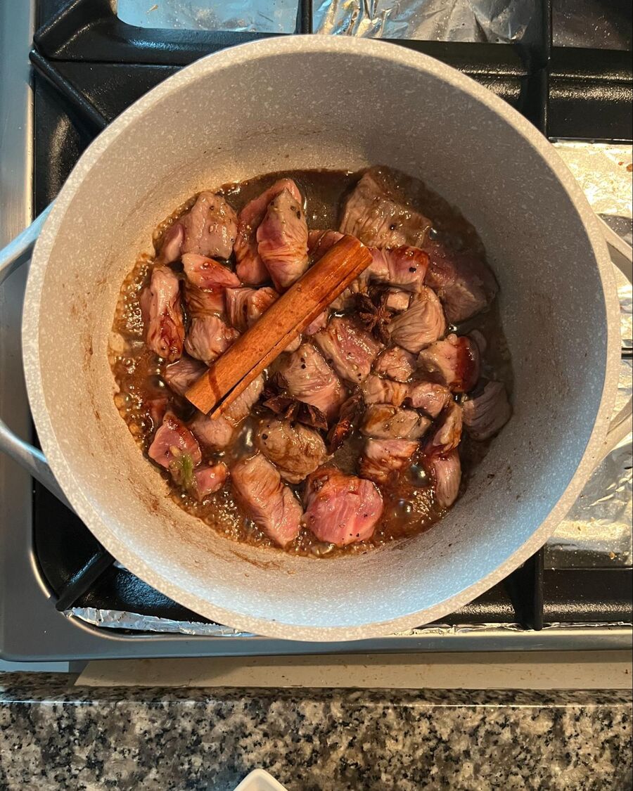 Continue stirring the pork belly until it is half-cooked. Then, add the cinnamon stick.