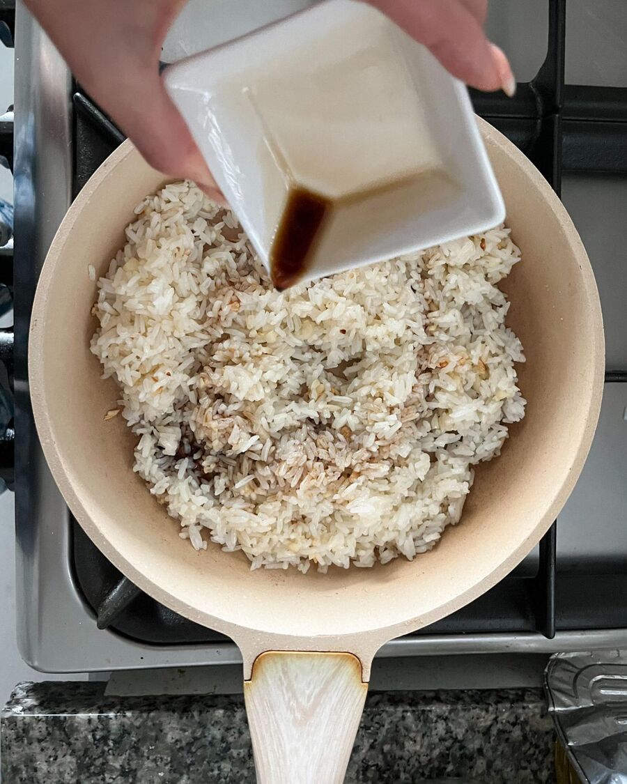 Add the chilled steamed rice to the pan. Then, add Takumi soy sauce, flavor seasoning powder, sugar, and a pinch of salt. Stir to combine everything until the rice is evenly coated with the sauce.