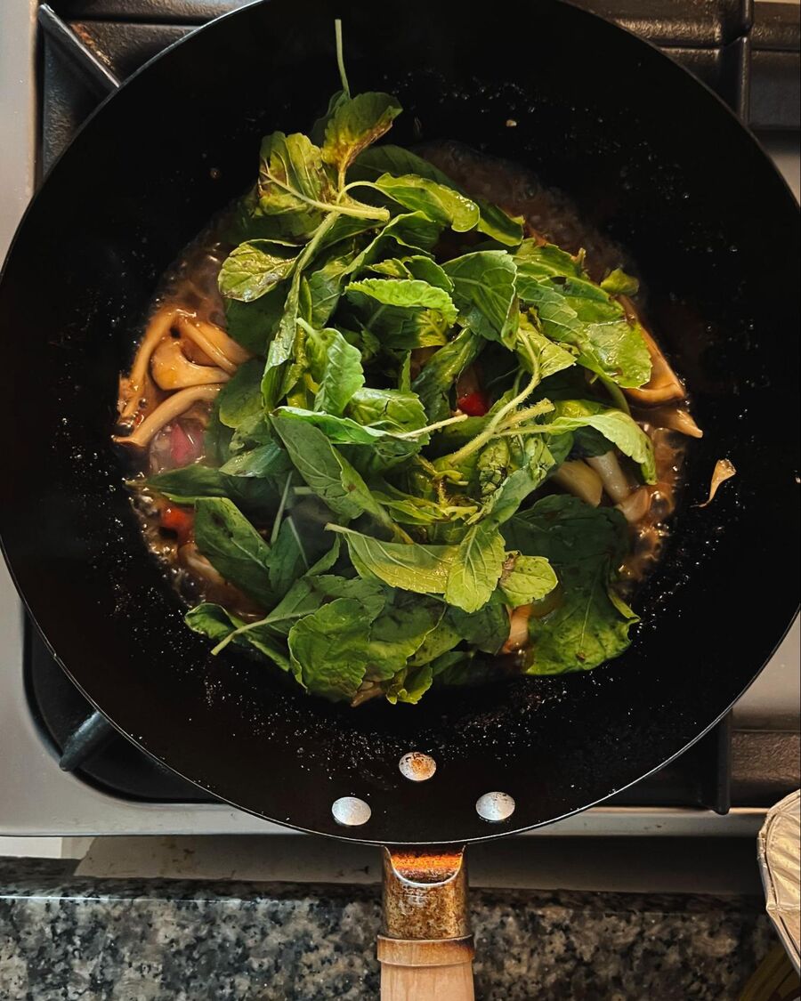 Sprinkle the Thai holy basil leaves over the mushrooms.