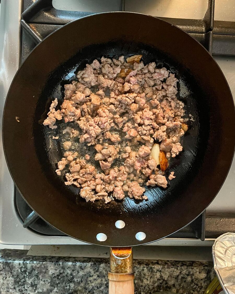 Add the minced pork to the pan and continue to stir until it is fully cooked.
