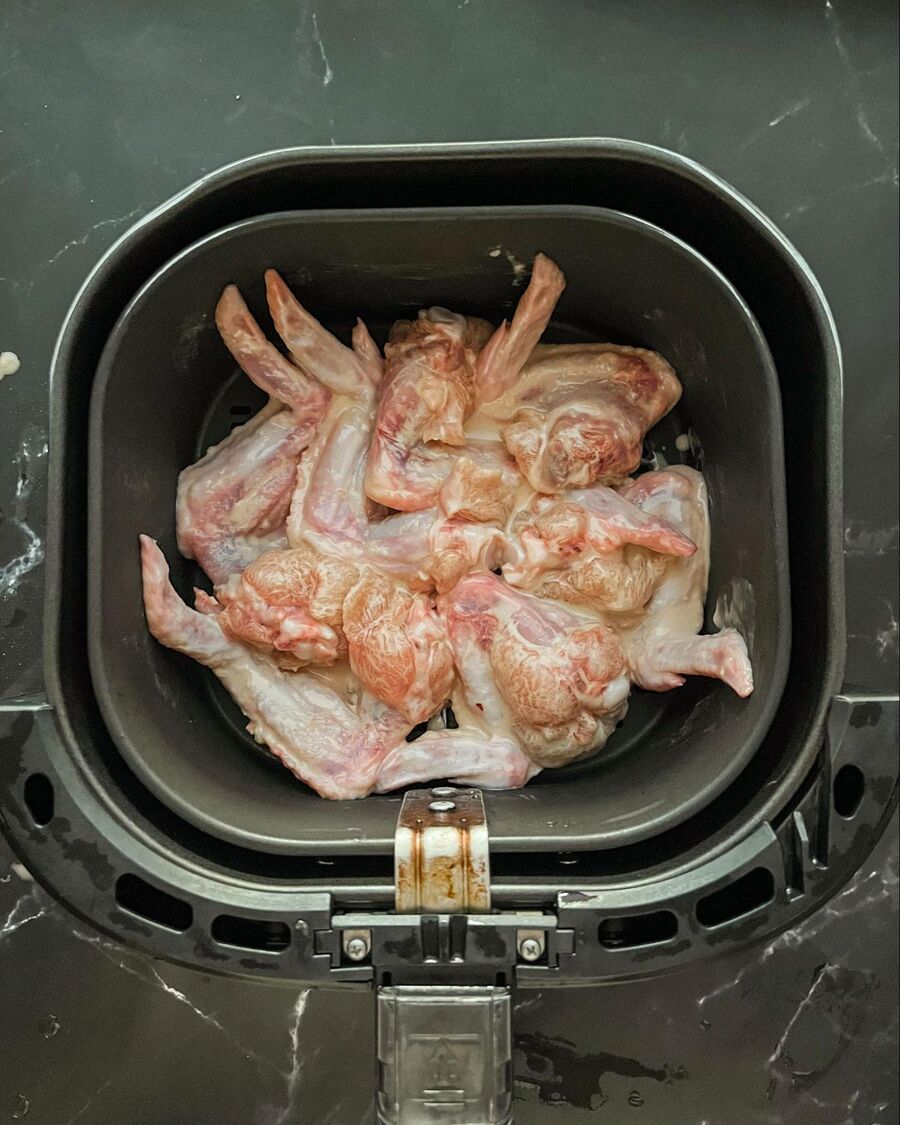 Place the chicken wings in the air fryer in a single layer, ensuring they don't overlap. Air fry at 180°C (356°F) for about 10 minutes.