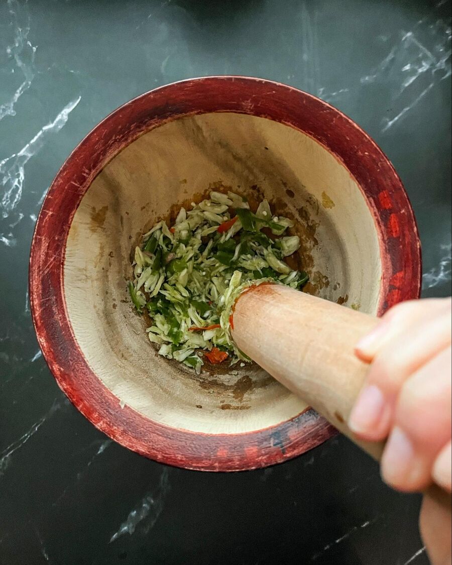 Peel the garlic and add it along with the chilies to a mortar. Pound until well combined and no large chunks remain.