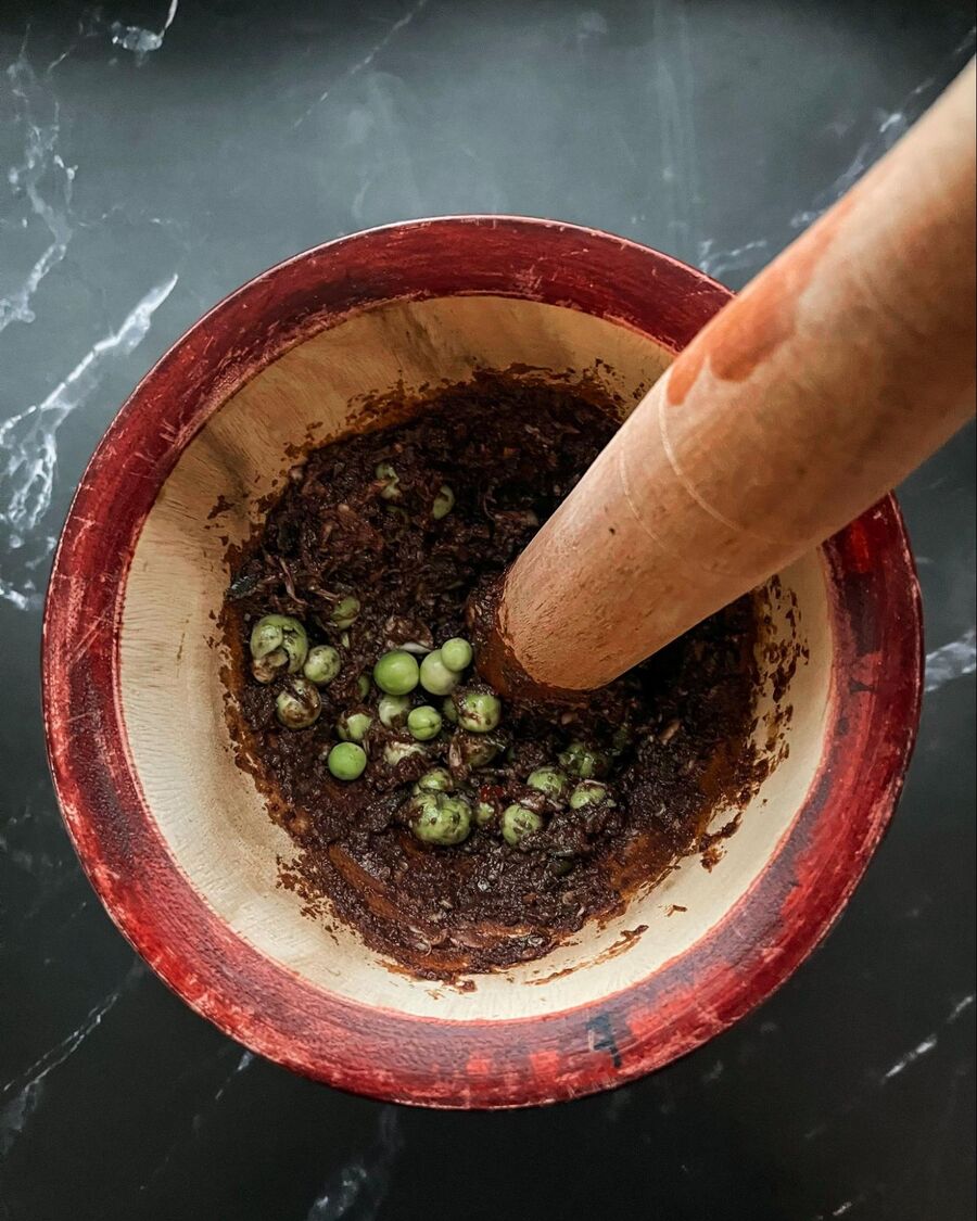 Add about 20 pea eggplants to the mortar and gently crush them—just enough to release the seeds.