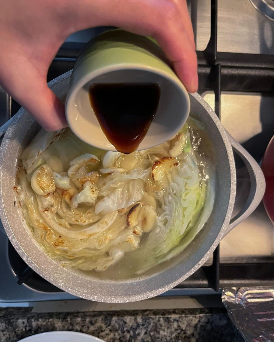 Transfer the grilled cabbage and garlic to the pot with the ribs. Add soy sauce, oyster sauce, and a shiitake mushroom stock cube.