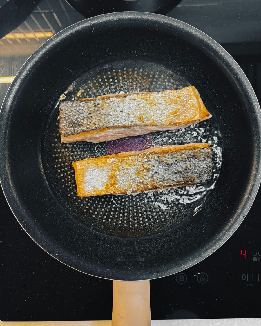 Cook the salmon fillets by first patting the skin dry with a paper towel. Heat a little cooking oil in a pan over medium-high heat. Place the salmon skin-side down and cook for 5 minutes, then flip and cook the other side for another 3 minutes.